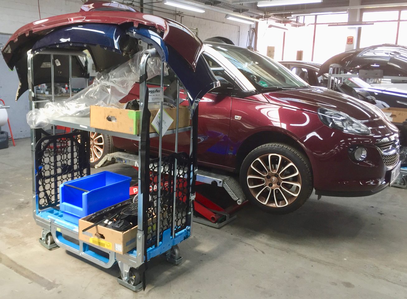 Loggyflex Duo mit Heckklappenteilen und Sortierkästen neben einem Fahrzeug in der Karosseriewerkstatt