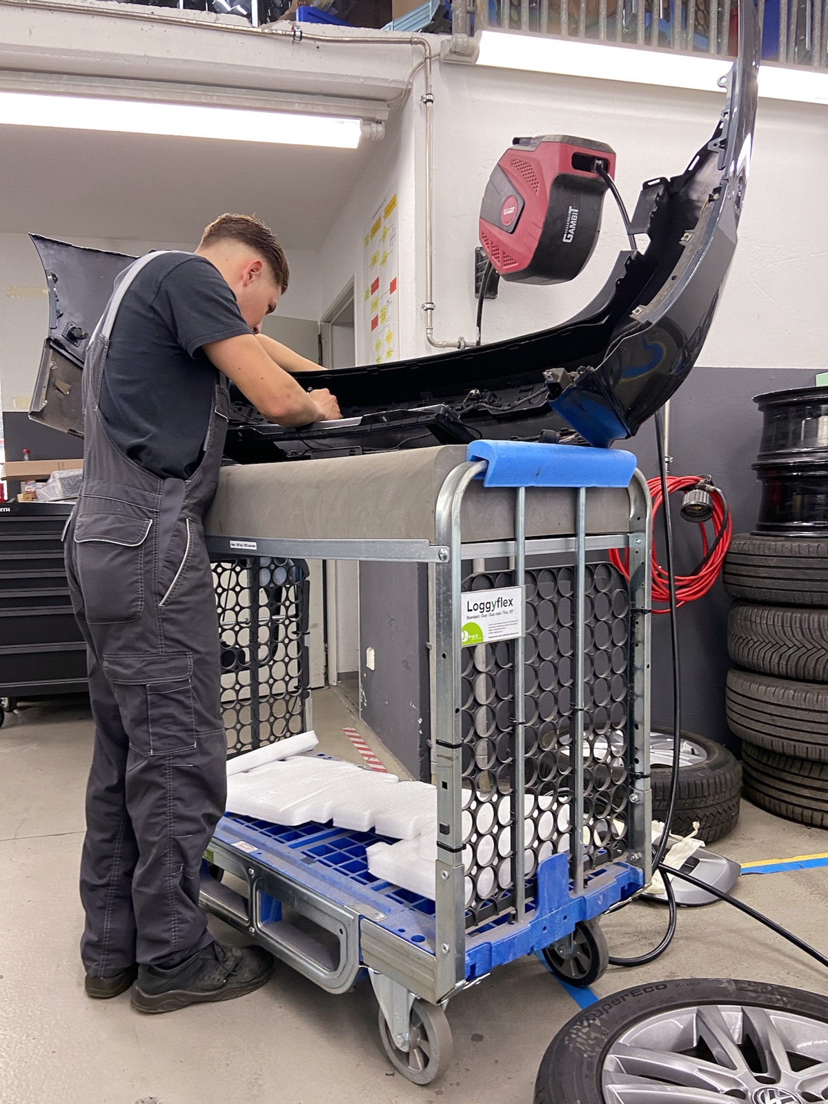 Mechaniker montiert einen Stoßfänger auf dem Loggyflex Duo mini, SoftTops schützen die Kante